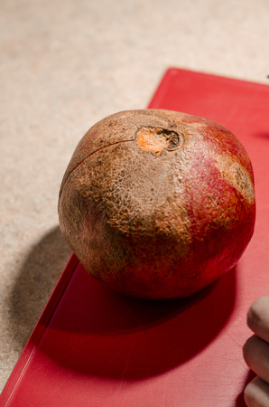 Ripe pomegranate fruit on the red cutting board. The background is red. Fresh organic food close up. Stay healthy concept.の写真素材