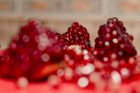 Fresh pomegranate seeds on the red cutting board. The background is white. Ripe organic food close up. Stay healthy concept.の写真素材