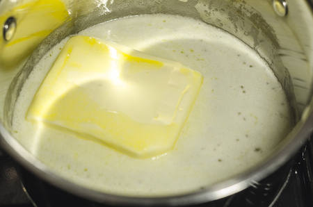 Melting butter or margarine in the pan on the stove. Process of cooking concept. Kitchen culinary close up view.の写真素材