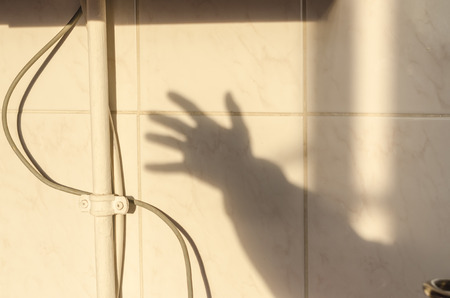 Human shadow of the hand waving on the wall. House or room interiors. Texture background of...