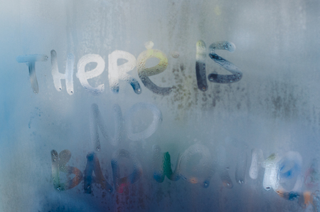 There is no bad weather in nature written on the foggy window. Water droplets condensation background of dew on glass, humidity close up view. Outside the house. Be happy even in bad raining weather concept.の写真素材