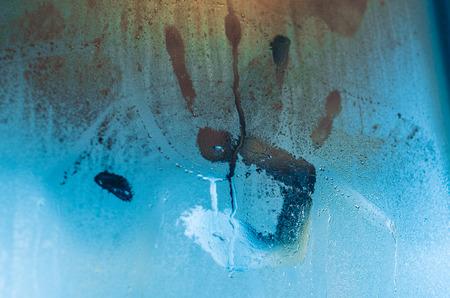 Handprint or palmprint left on the foggy window. Water droplets condensation background of dew on glass, humidity and foggy close up view. Outside the house, bad raining weather.の写真素材