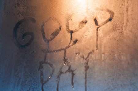 Good day with smilig face written on the foggy window. Water droplets condensation background of dew on glass, humidity and foggy close up view. Be happy even in bad raining weather outside concept.の写真素材