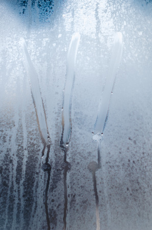 Three exclamation marks on the foggy window. Water droplets condensation background of dew on glass, humidity and foggy close up view. Outside the house. Attention bad raining weather.の写真素材