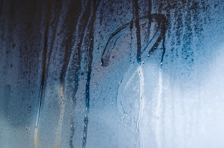 Drawn question mark on the foggy window. Water droplets condensation background of dew on glass, humidity and foggy close up view. Outside the house, bad raining weather.の写真素材