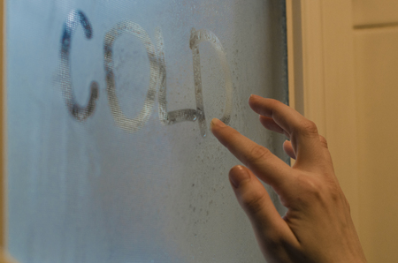 Human hand writing word Cold on the foggy window. Water droplets condensation background of dew on glass, humidity and foggy close up view. Outside the house, bad raining weather.の写真素材