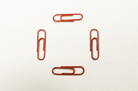 Red paperclips in the shape of the square isolated on the white background. School supplies and education stuff.の写真素材