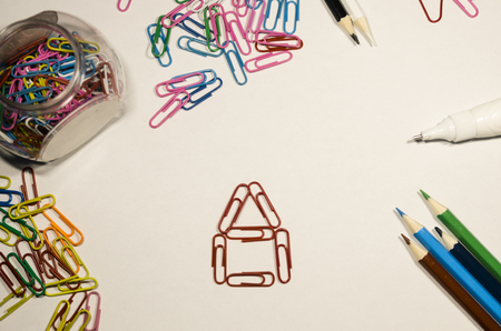 Colored paperclips in shape of the small house isolated on the white background. School supplies and education stuff. Creativity concept.の写真素材