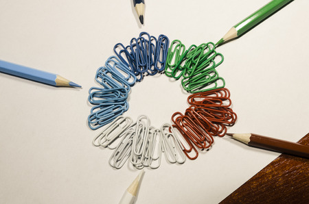 Colored paperclips in a circle and pencils isolated on white background. Be creative concept. School supplies or stuff. Education or business background.の写真素材