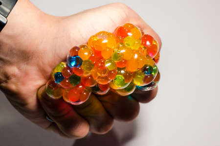 Colored antistress in the human hand isolated on the white background. Squeezing a toy with your palm. Stay relaxed concept.の写真素材