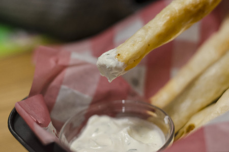 Potato or cheese sticks and the white sauce in the basket close up view. Eating fast food with mayonnaise concept. Unhealthy crispy snack.の写真素材