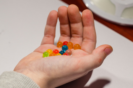 Colored balls of hydrogel in the human hands isolated on the white background. Growing water balls close up view.の写真素材