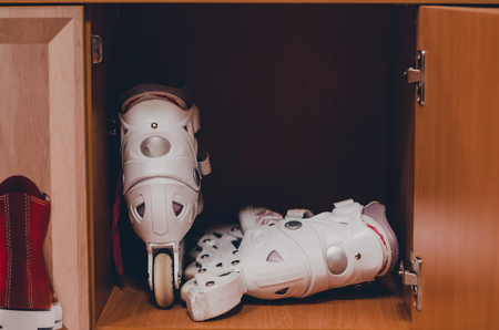 A pair of white roller skates in the wooden shelf close up view. Skating and havng fun concept. Keeping sport equipment in the locker.の写真素材