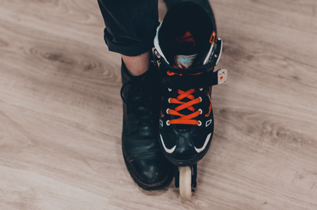 One leg in black roller skate and the other one in the shoe. Skating on roller rink concept. Doing sports and having fun.の写真素材