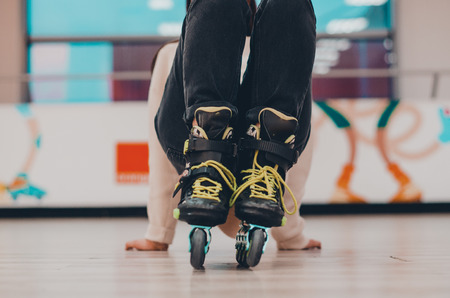 A human wearing black old roller skates on the roller rink from the front view. Green laces and wheels close up view. Ready to skate concept.の写真素材