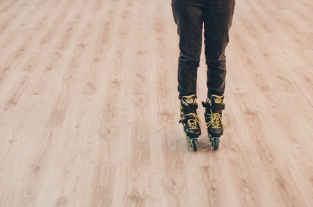 A human wearing black old roller skates on the roller rink from the front view. Green laces close up...
