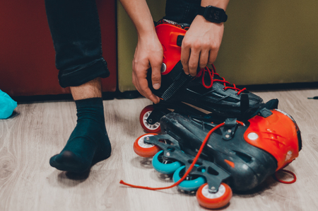 Changing shoes to roller skates on roller rink. A man putting on black skates and setting of laces concept.の写真素材