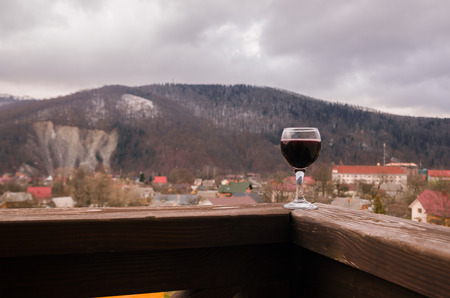 A glass of red wine on background of mountains. Drink wine in the mountains concept. Nature landscape of spring season. Alcohol drinks.の写真素材