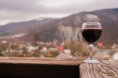 A glass of red wine on background of mountains. Drink wine in the mountains concept. Nature landscape of spring season. Alcohol drinks.の写真素材