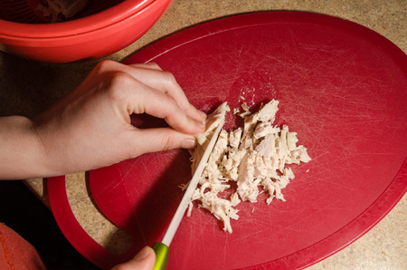 A hand cutting with a knife boiled chicken breast concept. Stay healthy and eat fresh organic food. The process of cooking diet food concept. Culinary view in the kitchenの写真素材