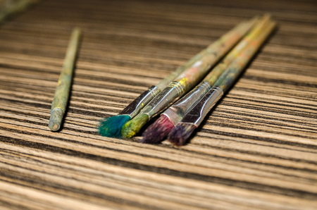 A collection of paint brushes and one broken brush apart on the wooden background. Art equipment for drawing.の写真素材