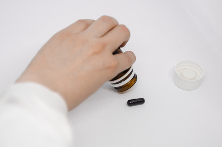 A hand spilling pills out of pill bottle concept. Medicine background isolated on the white paper....