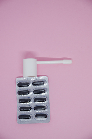 A packing of medical pills and nose drops. Medicine concept isolated on the pink background. Cure...