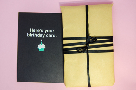 A handmade gift in brown wrapping paper and with black ribbon. A present with a postcard for...