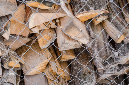 Wood pile reserve for the winter concept. Pile of chopped firewood from trees. Nature background texture of wood.  Wooden logs wall close up view behing the grid.の写真素材