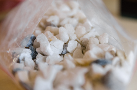 Texture background of white little stones. Mosaic structure decor . Scatter stones from plastic bag on the tableの写真素材