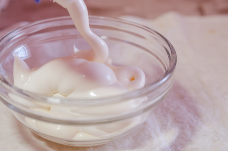 a glass bowl with mayonnaise close up view. Pouring white sauce in saucer concept.の写真素材