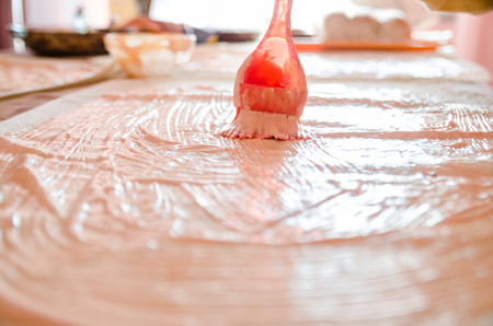 The process of cooking chicken wrap on kitchen table at home concept. Homemade kebab close up. Fresh thin pita bread of shawarma sandwich with mayonnaise and ketchup . Hands lubricating lavash.の写真素材