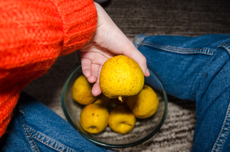 shriveled yellow apples in hand and in the glass bowl. Old and dried fruits concept.