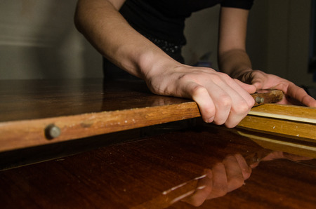 A man repairing one old wooden table at home. Repair or overhaul concept.の写真素材