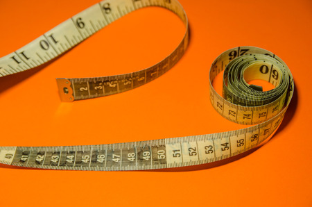 measuring tape in roll isolated on orange background.の写真素材