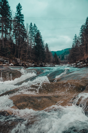river in the mountains of bukovel with swirling stream of water. Big boulders in winter mountain...