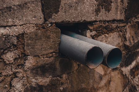 two small tubes in a hole of the brick wall. sewer pipes for water passage outsideの写真素材