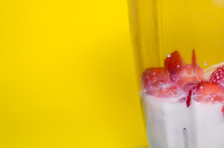 mixing stawberries and bananas with milk in glass blender concept. milkshake with copy space