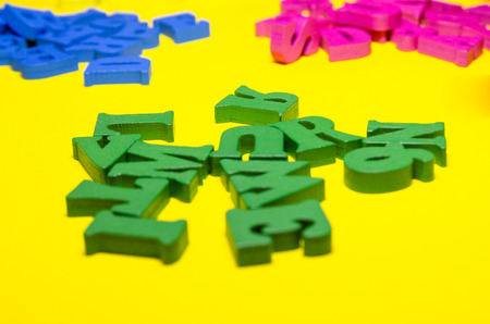 wooden letters on the yellow background. three groups of colors