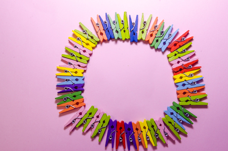 pink background of a circle made out of colored clothespins or pegs with copy spaceの写真素材