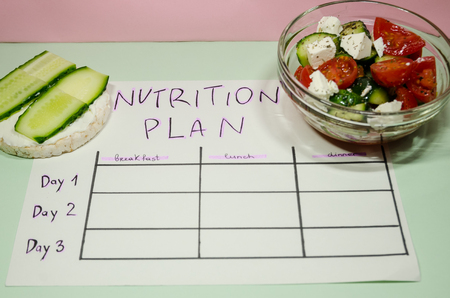 background of blank nutrition plan with copy space, red dumbbell and organic salad. Diet food and loosing weight control concept. Puffed rice bread sandwich.の写真素材