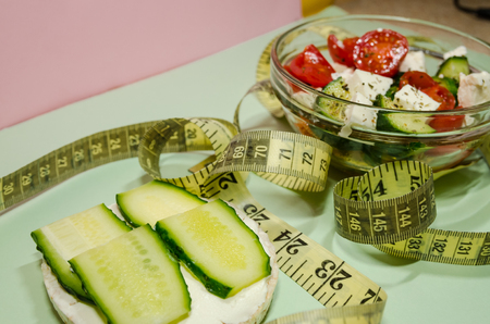 background of organic salad of tomatoes and cucumbers with a measuring tape and puffed rice breads. Diet and loosing weight concept.の写真素材