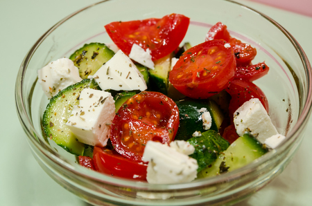 Blue background of organic salad of tomatoes and cucumbers in glass bowl with copy space. Healthy lifestyle concept.の写真素材