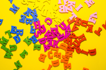 the mess of colored alphabetic letters on yellow background from top viewの写真素材