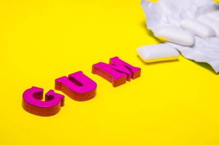 word gum compossed with wooden pink letters. white pads of chewing gumの写真素材