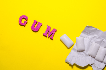 word gum compossed with wooden pink letters. white pads of chewing gumの写真素材