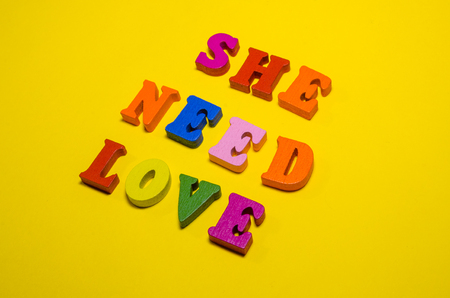 she needs love written with wooden colored lettersの写真素材