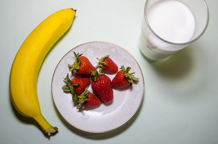 milkshake ingredients. glass cup of milk, strawberries and bananas on background.の写真素材