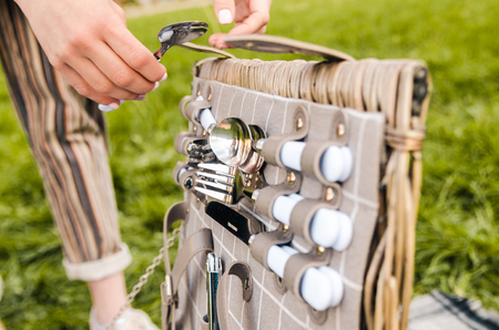 woman taking silver spoon from the picnic basket outside on green grass.の写真素材