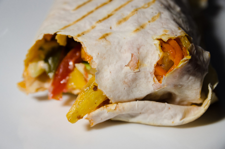 bitten shawarma with chicken on white plateの写真素材